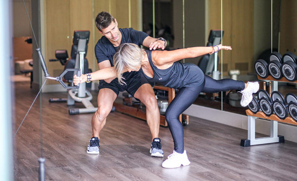 Entraînement personnalisé Athomic Wellness : un coach accompagne une cliente dans un exercice de force et d’équilibre pour libérer son plein potentiel.